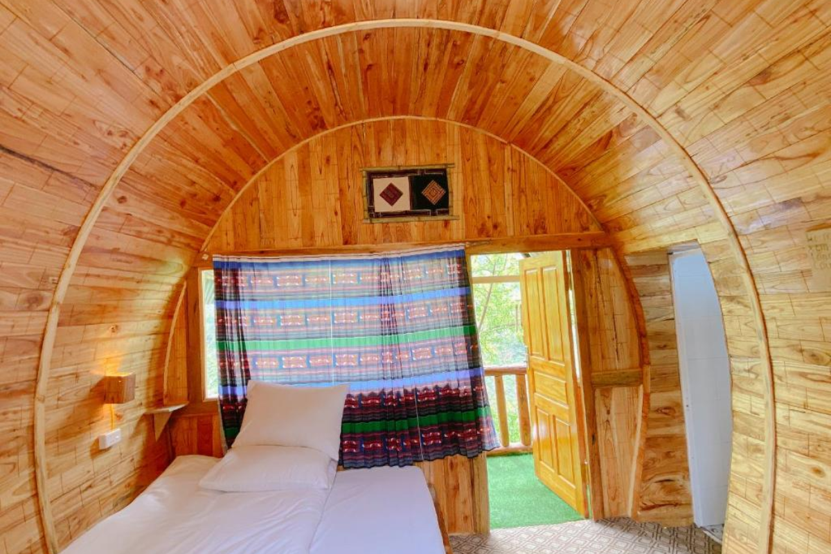 A Hoà Homestay's traditional wooden home surrounded by trees in Lai Chau